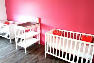 Salle de jeux lumineuse avec une cabane en tissu, un tapis de chiffres, une cuisine pour enfants et des tables colorées.