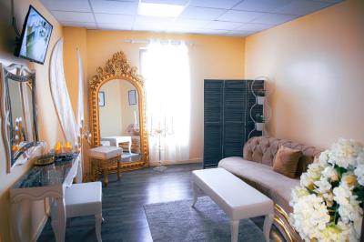 Salle de jeux lumineuse avec une cabane en tissu, un tapis de chiffres, une cuisine pour enfants et des tables colorées.