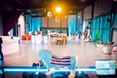 Terrasse avec tables, chaises et parasols, bordée d'une pelouse et d'un bâtiment moderne, sous un ciel ensoleillé.