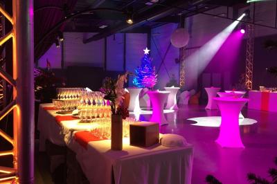 Terrasse avec tables, chaises et parasols, bordée d'une pelouse et d'un bâtiment moderne, sous un ciel ensoleillé.