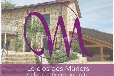 Façade en pierre d'une maison rénovée avec terrasse, grandes fenêtres et espace extérieur gravillonné.