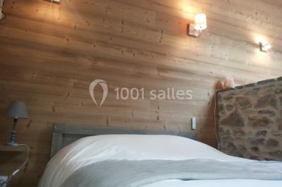 Façade en pierre d'une maison rénovée avec terrasse, grandes fenêtres et espace extérieur gravillonné.