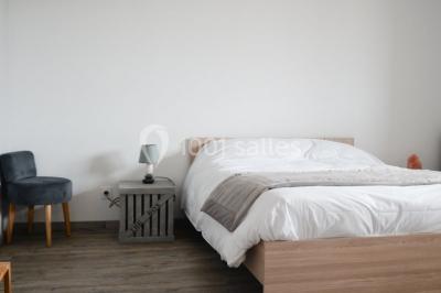 Façade en pierre d'une maison rénovée avec terrasse, grandes fenêtres et espace extérieur gravillonné.