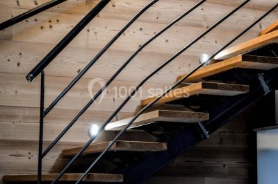 Façade en pierre d'une maison rénovée avec terrasse, grandes fenêtres et espace extérieur gravillonné.