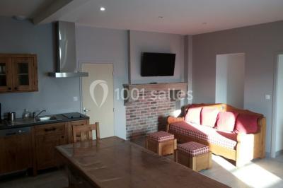 Façade en pierre d'une maison rénovée avec terrasse, grandes fenêtres et espace extérieur gravillonné.