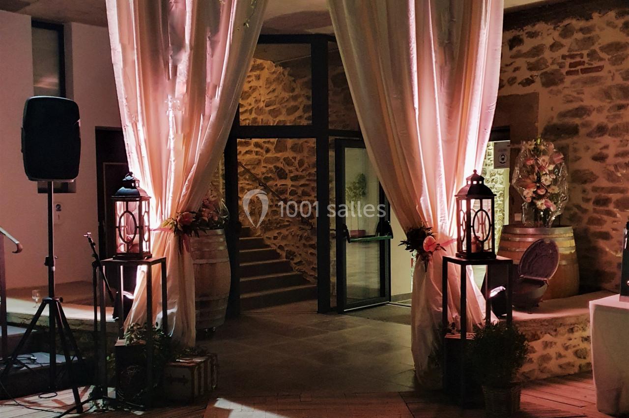 Entrée décorée avec des rideaux roses, guirlandes lumineuses et lanternes, menant à un espace intérieur en soirée.