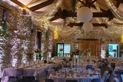 Façade en pierre d'une maison rénovée avec terrasse, grandes fenêtres et espace extérieur gravillonné.