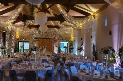 Façade en pierre d'une maison rénovée avec terrasse, grandes fenêtres et espace extérieur gravillonné.