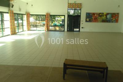 Phare blanc sur un îlot rocheux, accessible par une jetée étroite, entouré d'eau sous un ciel bleu clair.