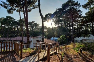 Phare blanc sur un îlot rocheux, accessible par une jetée étroite, entouré d'eau sous un ciel bleu clair.
