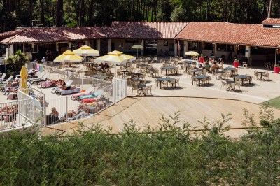 Phare blanc sur un îlot rocheux, accessible par une jetée étroite, entouré d'eau sous un ciel bleu clair.