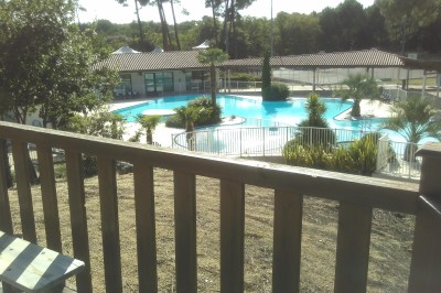 Phare blanc sur un îlot rocheux, accessible par une jetée étroite, entouré d'eau sous un ciel bleu clair.
