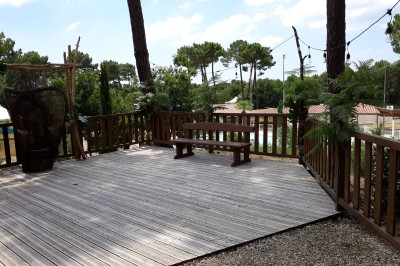 Phare blanc sur un îlot rocheux, accessible par une jetée étroite, entouré d'eau sous un ciel bleu clair.