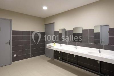 Chambre lumineuse avec deux lits, parquet au sol, murs clairs et fenêtres donnant sur un jardin verdoyant.