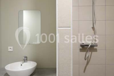 Chambre lumineuse avec deux lits, parquet au sol, murs clairs et fenêtres donnant sur un jardin verdoyant.