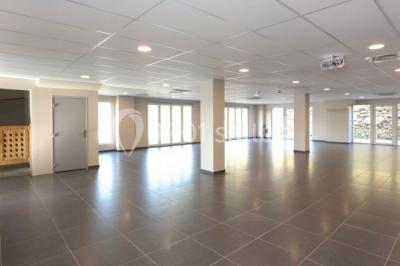 Chambre lumineuse avec deux lits, parquet au sol, murs clairs et fenêtres donnant sur un jardin verdoyant.