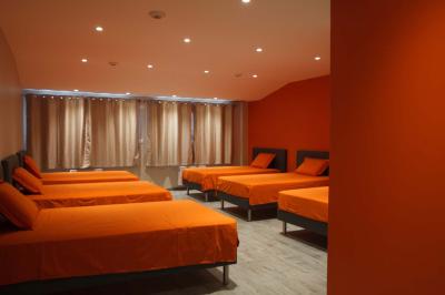 Chambre lumineuse avec deux lits, parquet au sol, murs clairs et fenêtres donnant sur un jardin verdoyant.