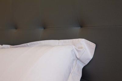 Chambre lumineuse avec deux lits, parquet au sol, murs clairs et fenêtres donnant sur un jardin verdoyant.