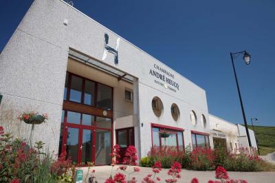 Chambre lumineuse avec deux lits, parquet au sol, murs clairs et fenêtres donnant sur un jardin verdoyant.