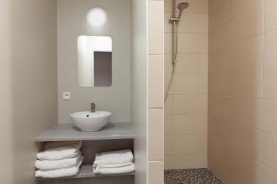 Chambre lumineuse avec deux lits, parquet au sol, murs clairs et fenêtres donnant sur un jardin verdoyant.