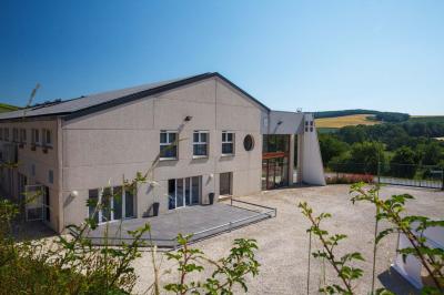 Chambre lumineuse avec deux lits, parquet au sol, murs clairs et fenêtres donnant sur un jardin verdoyant.