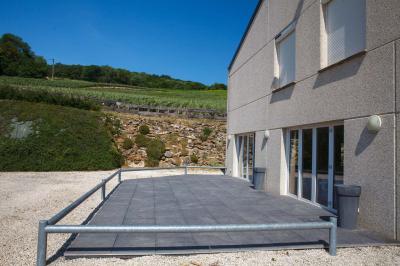 Chambre lumineuse avec deux lits, parquet au sol, murs clairs et fenêtres donnant sur un jardin verdoyant.