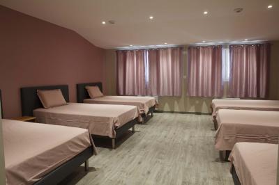 Chambre lumineuse avec deux lits, parquet au sol, murs clairs et fenêtres donnant sur un jardin verdoyant.