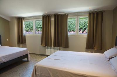 Chambre lumineuse avec deux lits, parquet au sol, murs clairs et fenêtres donnant sur un jardin verdoyant.