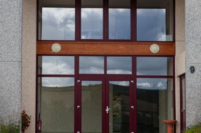 Chambre lumineuse avec deux lits, parquet au sol, murs clairs et fenêtres donnant sur un jardin verdoyant.