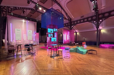 Salle intérieure avec mezzanine, escaliers symétriques, balustrades en métal décoratif et parquet au sol.