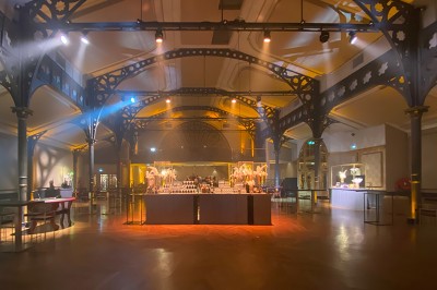 Salle intérieure avec mezzanine, escaliers symétriques, balustrades en métal décoratif et parquet au sol.