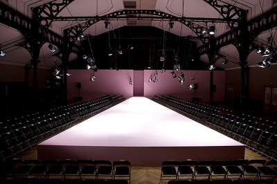 Salle intérieure avec mezzanine, escaliers symétriques, balustrades en métal décoratif et parquet au sol.