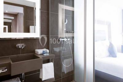 Salle de restaurant moderne avec tables dressées, chaises colorées, suspensions lumineuses et grandes baies vitrées.