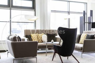 Salle de restaurant moderne avec tables dressées, chaises colorées, suspensions lumineuses et grandes baies vitrées.