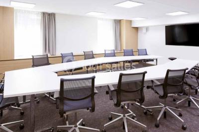 Salle de restaurant moderne avec tables dressées, chaises colorées, suspensions lumineuses et grandes baies vitrées.