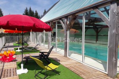 Trois petits chalets colorés en bois, entourés d'arbres et de pelouse, sous un ciel dégagé.
