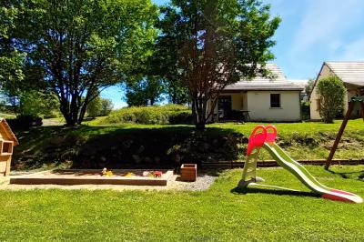 Trois petits chalets colorés en bois, entourés d'arbres et de pelouse, sous un ciel dégagé.