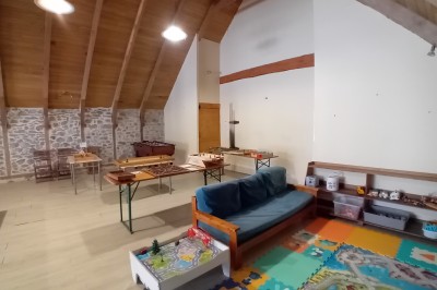 Trois petits chalets colorés en bois, entourés d'arbres et de pelouse, sous un ciel dégagé.