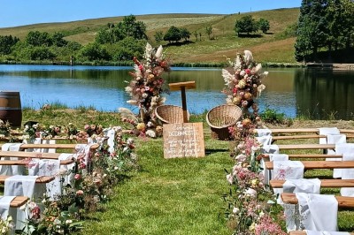 Trois petits chalets colorés en bois, entourés d'arbres et de pelouse, sous un ciel dégagé.