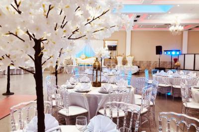 Salle de réception décorée avec une table dressée, un centre de table floral et une arche fleurie en arrière-plan.