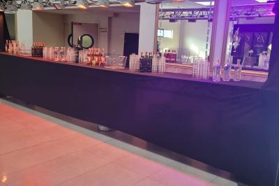 Salle de réception décorée avec une table dressée, un centre de table floral et une arche fleurie en arrière-plan.