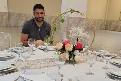 Salle de réception décorée avec une table dressée, un centre de table floral et une arche fleurie en arrière-plan.