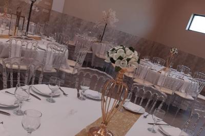 Salle de réception décorée avec une table dressée, un centre de table floral et une arche fleurie en arrière-plan.