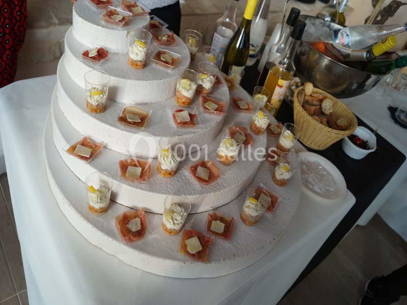 Présentoir en étages avec verrines de saumon et fromage, entouré de bouteilles de vin et d'un panier de pain.