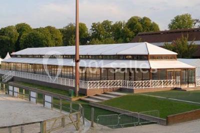 Chambre d'hôtel lumineuse avec lit double, bureau bleu, fauteuil, télévision et balcon offrant une vue sur l'extérieur.