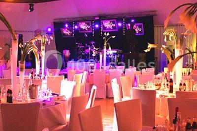 Chambre d'hôtel lumineuse avec lit double, bureau bleu, fauteuil, télévision et balcon offrant une vue sur l'extérieur.