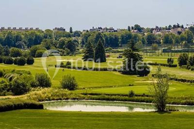 Chambre d'hôtel lumineuse avec lit double, bureau bleu, fauteuil, télévision et balcon offrant une vue sur l'extérieur.