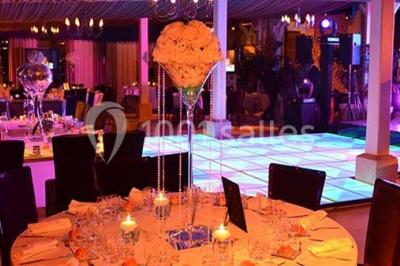 Chambre d'hôtel lumineuse avec lit double, bureau bleu, fauteuil, télévision et balcon offrant une vue sur l'extérieur.