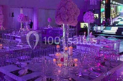Chambre d'hôtel lumineuse avec lit double, bureau bleu, fauteuil, télévision et balcon offrant une vue sur l'extérieur.