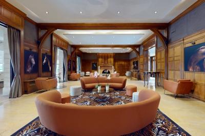 Chambre d'hôtel lumineuse avec lit double, bureau bleu, fauteuil, télévision et balcon offrant une vue sur l'extérieur.